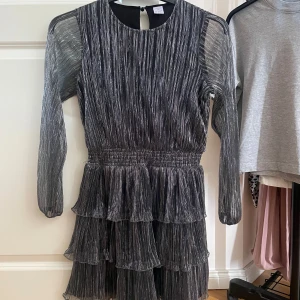 Glitterklänning från Lindex - Säljer denna super fina glitter klänningen från Lindex. Den har använts 2ggr och är i super bra skick. Den är i storleken 146/152 men passar en xxs - xs. Den har även volanger nertill.