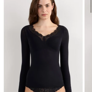 Svart långärmad topp med spets - Svart långärmad topp med djup v-ringning och snygga spetsdetaljer vid halsringning och ärmslut. Figurnära passform som sitter snyggt på kroppen. Perfekt att styla med jeans eller kjol för en trendig look. Vill ni ha bilder på min egna är det bara o skriva 