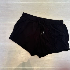 Svarta shorts med snörning - Svarta, mjuka Hm shorts med elastisk midja och snörning framtill med silvrig detalj.
