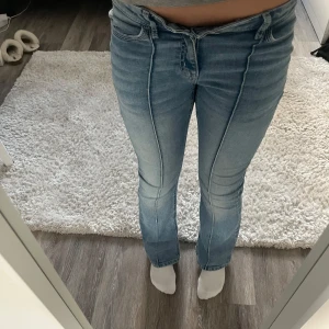 Ljusblå bootcut jeans från Lindex - Snygga ljusblå jeans från Lindex med bootcut och mid waisted. Jeansen har markerade sömmar framtill och bakfickor med dekorativ knapp.  Jeansen är från Lindex i modell Freja och är k strl 164.