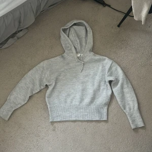 Ljusgrå stickad hoodie från Gina Tricot - Supermjuk ljusgrå hoodie från Gina Tricot i stickat material. Perfekt för dig som gillar en chill och enkel stil. Passar dig som vill ha en lite kortare modell. Säljer eftersom den aldrig har kommit till användning 