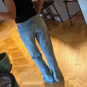 Ljusblå raka jeans med normal midja - Säljer ett par ljusblå jeans med klassisk femficksdesign och normal midja. Jeansen har raka ben och en avslappnad passform, perfekta för en chill och stilren look. Tillverkade i mjukt denimtyg som känns skönt hela dagen.