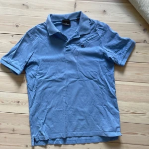 Blå pikétröja från Scotch & Soda - Ljusblå pikétröja från Scotch & Soda i ekologisk bomull. Klassisk krage, korta ärmar och liten broderad logga på bröstet. Perfekt basic med snygg passform och stilren look.