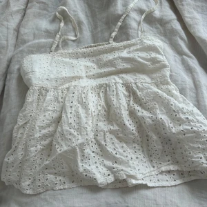 Vit topp med broderi - Supersöt vit topp med tunna axelband och broderade hålmönster. Luftig och lätt med volangig, 💕