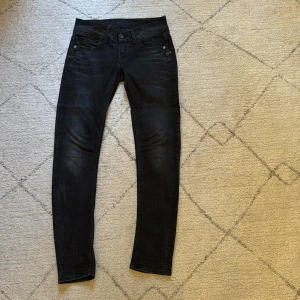 Svarta jeans från G-Star RAW - Säljer ett par svarta jeans från G-Star RAW med snyggt tvättad look och klassiska fem fickor. Jeansen har raka ben, normal passform och coola detaljer som logotyp på fickan och bak på linningen. Använda mycket men har varit väl omhändertagna samt inga defekter på jeansen. Hör av er vid frågor. Nypris cirka 1000kr. 