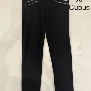 Svarta byxor med dragkedjor Cubus - Svarta byxor från Cubus i storlek XL med snygga dragkedjedetaljer framtill. Byxorna har en rak passform och är perfekta för en clean och stilren look. Materialet känns mjukt och stretchigt, vilket gör dem bekväma att bära hela dagen.