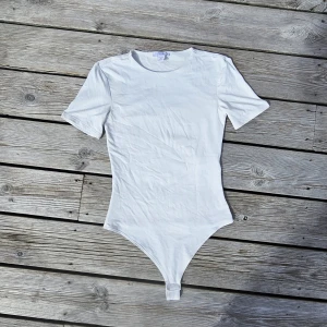 Vit body - En vit t-shirt body från Amisu i storlek XS, använd endast nån gång. Jätte fint skick! Dubbeltyg så är inte det minsta genomskinlig ❤️🙏🏻 - finns en likadan svart upplagd med!