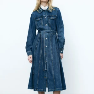 KÖPES! Lång jeansklänning med bälte & knappar - KÖPES! Lång jeansklänning från H&M i klassisk blå denim. Strl S. Klänningen har långa ärmar, markerad midja med avtagbart bälte och lätt utställd kjol. 