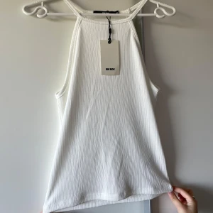 Vit ribbad linnetopp från Bik Bok - Snygg vit ribbad linnetopp från Bik Bok med hög hals och ärmlös design. 