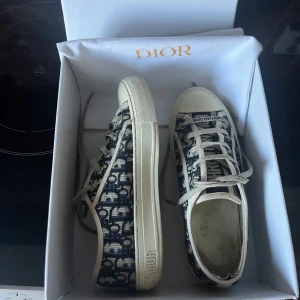 Dior Walk'n'Dior sneakers i blått mönster - Säljer ett par Dior Walk'n'Dior sneakers i storlek 38. Skorna är stora i storleken så skulle säga storlek 39, innersula:24.5cm. Inga större skador som syns men är väl använda❣️låda och dustbag medföljer. Serienummer syns på bilden