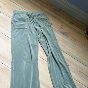 Gröna mjukisbyxor Juicy Couture - Snygga gröna mjukisbyxor från Juicy Couture med broderad JC-logga på fickan. Byxorna har bred resår i midjan med snörning och raka ben. Mjukt och lent material. En metall bit har lossnat vid snörningen men inte något som gör någon skillnad vid användning, org pris ca 600kr