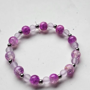 Lila pärlarmband med glittriga detaljer - Snyggt armband med lila och ljuslila pärlor, varvat med små silvriga kulor. De större pärlorna har en glittrig, sprucken effekt som ger extra bling.
