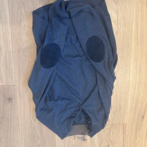 Mörkblå kofta med armbågslappar från Massimo dutti  - Snygg mörkblå kofta med klassiska armbågslappar i matchande färg. Koftan har knappar framtill och ribbade muddar vid ärmslut och nederkant. Perfekt för dig som gillar en stilren och chill look.