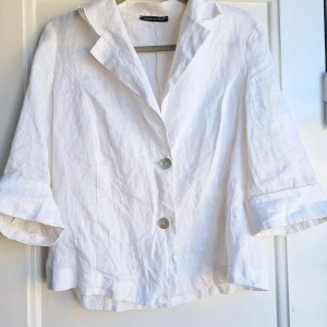 Vit linnekavaj Made in Italy - Stilren vit kavaj i linne med trekvartsärm och två knappar framtill. Klassisk krage och avslappnad passform, perfekt för en fräsch och luftig look. Snygga detaljer vid ärmslut och lätt struktur i tyget. Enkel att matcha till olika outfits.