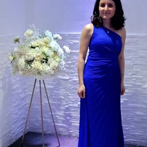 Kornblå långklänning oneshoulder - Snygg långklänning i kornblått med oneshoulder-design och draperade detaljer. Klänningen har en elegant, figurnära passform och är perfekt för speciella tillfällen. Materialet känns mjukt och följsamt mot kroppen.