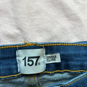 Blå flare jeans från 157 - Snygga blå jeans från 157 med flare-ben, högre midja, nere vid benen ska de egentligen vara uppvikt då de är uppsydda men går enkelt att sprätta upp. Pris kan diskuteras!