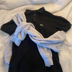 Svart pikétröja från Lacoste - Svart piké från Lacoste, nästan oanvänd och i perfekt skick, inga slitage. Storlek är 12 år/152 cm. Skriv gärna vid frågor eller bud