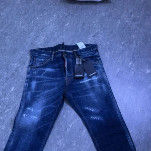Mörkblå jeansbyxor från Dsquared2 - Säljer ett par mörkblå jeansbyxor från Dsquared2 med slitna detaljer och klassisk femficksmodell. Byxorna har en normal passform och tydliga tvättade partier för en cool look. Perfekta för dig som gillar streetstil. Inte använda alls och helt nya. Är lite osäker på storleken men jag har s-m så lägger de på s/m.
