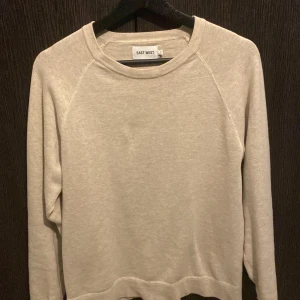 Beige sweatshirt från EAST WEST - Säljer en stilren beige sweatshirt från EAST WEST. Tröjan har rund halsringning och långa ärmar. Perfekt för en avslappnad och enkel look. Mjuk och bekväm, passar till det mesta. Perfekt för sommaren