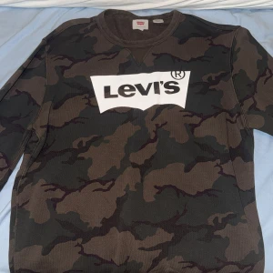 Camouflage sweatshirt från Levi's - Säljer en snygg sweatshirt från Levi's med camouflage-mönster i gröna och bruna toner.