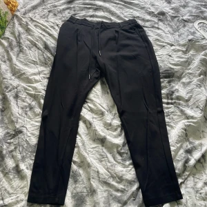 Svarta byxor med snörning - Svarta byxor med rak passform och dragsko i midjan. Byxorna har diskreta fickor och är perfekta för en avslappnad men stilren look. Har tre likadana annonser för har tre par av byxorna hemma