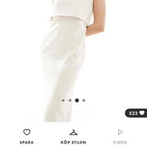 Vit axelbandslös långklänning med knappar - Säljer en elegant vit långklänning med axelbandslös design och dekorativa knappar framtill. Klänningen har en figurnära passform och är perfekt för speciella tillfällen. Materialet är slätt och ger en lyxig känsla. Den är helt oanvänd alla lappar finns kvar 