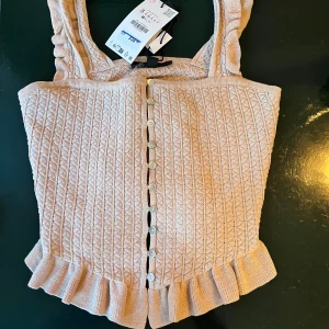 Beige stickad linnetopp med volang och knappar - Supersöt beige stickad linnetopp. Helt ny från Zara med prislappen kvar. Säljer för 290 istället för 329