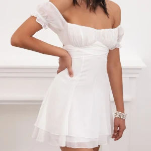 Studentklänning  - Kort somrig klänning med omlottknytning, skir volangkjol och puffiga ärmar. Går att ha både off shoulder och kortärmad. Perfekt för sommarens alla tillfällen!🌸