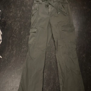 Olivgröna cargopants från OXXO - Säljer ett par olivgröna cargopants från OXXO i storlek XS. Byxorna har flera fickor, knytband i midjan och raka ben. Perfekta för en avslappnad och trendig stil.