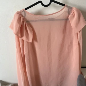 Ljusrosa blus  - Säljer en ljusrosa blus från BikBok med transparent tyg och korta, puffiga ärmar. Blusen har en lös passform och är perfekt för vår och sommar. Enkel och stilren design som passar till många tillfällen.