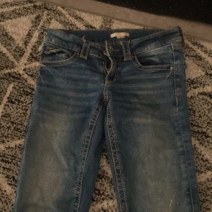 Blå jeansbyxor från Gina Tricot - Säljer ett par klassiska blå jeans från Gina Tricot med normal passform. Byxorna har fem fickor, bälteshällor och dragkedja med knapp framtill. Perfekta till vardags och enkla att matcha med olika toppar.