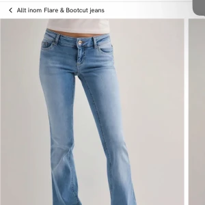 Ljusblå bootcut jeans - Säljer ett par ljusblå bootcut jeans med klassisk femficksdesign och knappgylf. Jeansen har en låg midja och lätt utsvängda ben, vilket ger en snygg siluett. Perfekta till sneakers eller boots.