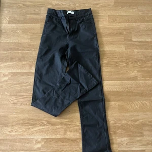 Svarta jeans med utsvängda ben - Svarta byxor med normal midja. Perfekt för en clean och stilren look. Fickor fram och bak samt hällor för bälte.