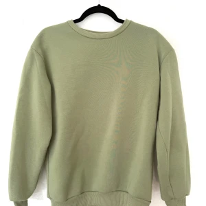 Ljusgrön sweatshirt, stl S - Enkel och stilren ljusgrön sweatshirt med rund halsringning och ribbade muddar. Tröjan är mjuk och har en relaxed passform som passar perfekt till jeans eller mjukisbyxor. Perfekt för dig som gillar en clean och chill look.
