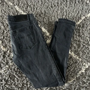 Svarta jeans från Tiger of Sweden - Snygga svarta jeans från Tiger of Sweden med klassisk femficksdesign och diskret logga på bakfickan. Jeansen har slim passform och är tillverkade i stretchigt jeanstyg för en bekväm känsla. Modell: Slim, Storlek: 32/32