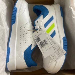 Adidas Tensaur Sport 2.0 sneakers blå/vit - Helt Nya Fräscha Adidas Tensaur Sport 2.0 sneakers i vitt och blått med limegröna detaljer. Skorna har klassiska tre ränder på sidan, snörning och slitstark syntetöverdel. Perfekta för träning eller vardag, med bekväm passform och greppvänlig sula.