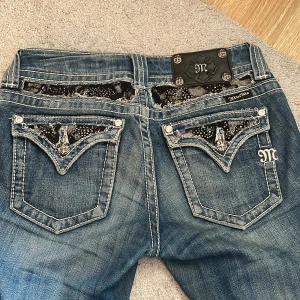 Miss Me jeans med detaljerad bakficka - Säljer dessa då de har blivit för små för mig. Köpte dom för ungefär två år sen här på plick o har använt dom väldigt mycket. Dragkedjan har varit trasig ända sen jag köpte dom men den går att stänga om man ”hakar” fast båda sidor av dragkedjan. (Kan skicka bild privat då jag inte kan lägga ut fler bilder). De sprack mellan benen men jag har försökt laga dom så bra som möjligt (se bild 4). Annars är dom i jättefint skick. Skriv privat för mått osv. 😊❤️