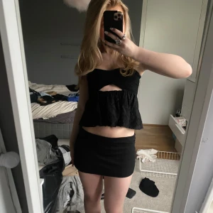 Svart bandeau topp från Zara - Supersöt svart bandeau topp från Zara med smockad överdel och volang nertill. Toppen är axelbandslös och har en snygg cut-out detalj framtill. 