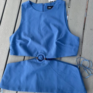 Blå topp med ringdetalj från Zara - Supersnygg blå topp från Zara med ärmlös design och cool cut-out vid midjan med ringdetalj framtill. Toppen har dragkedja i ryggen. Perfekt för dig som vill sticka ut med en trendig look.