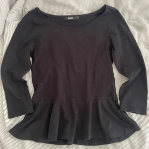 Svart topp  - Svart topp från Bik Bok med trekvartsärm och rundad halsringning. Toppen har en markerad midja och utsvängd nederdel som ger en snygg siluett. Perfekt att styla med jeans eller kjol för en trendig look.