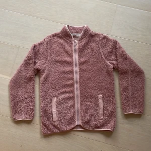 Rosa teddyjacka med dragkedja - Mysig rosa teddyjacka med hel dragkedja framtill och två fickor. 