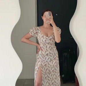 Blommig långklänning med slits - Supersnygg klänning i storlek XS från Shein, endast använd ett fåtal gånger och är i perfekt skick. Jag har sytt in och justerat baktill så att den kan knytas åt i midjan för en mer figurnära och snatched passform, då originalmodellen var lite för vid. Klänningen har även en dragkedja på sidan för enkel påklädning.