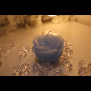 Blue Rose Candle - Shaped like a blooming rose and coated in a subtle shimmer, this pastel blue candle brings softness and serenity to any space. Lovely as a gift or a calming décor accent. Size - H: 5cm, L: 7cm