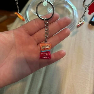 Nyckelring med Cheetos Party Size - Rolig nyckelring med en miniatyr av en Cheetos Party Size-påse i rött och orange. Perfekt accessoar för dig som älskar snacks och vill ha något unikt på dina nycklar eller väskan.