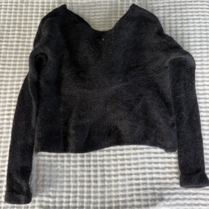 Svart omlottstickad tröja H&M XS - Mysig svart stickad tröja från H&M i alpackablandning. Tröjan har lång ärm och en snygg omlottdetalj framtill som ger en cool twist. Perfekt för lager-på-lager och funkar till både jeans och kjol.