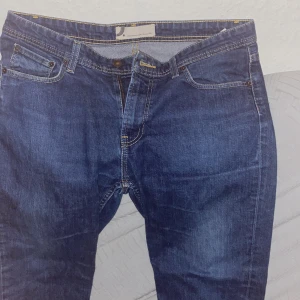 Mörkblå jeans från Dressmann - Snygga mörkblå jeans från Dressmann med klassisk femficksdesign och kontrastsömmar. Jeansen har rak passform och är tillverkade i slitstarkt denimtyg. Perfekta för dig som gillar en tidlös och enkel stil.