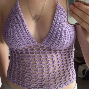 Ljuslila virkad croppad linnetopp - Superfin ljuslila virkad linnetopp med halterneck och djup v-ringning. Toppen är croppad och har ett öppet, nätliknande mönster ner till. Den har snörning i ryggen vilket gör att den är justerbar och kan ändras så att den passar på dig. Virkar även dessa på beställning.💗 Skicka om du har någon fråga!