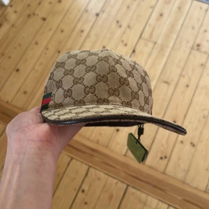 Gucci keps - Säljer min nya beige gucci keps för att jag inte gillade färgen. Den är aldrig använd och beskrvingings lapparna sitter fortfarande på kepsen. Priset är inte hugget i sten