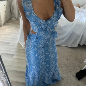 Blå långklänning från mango - Supersöt blå långklänning med vita broderade blommor, volangdetaljer och cut-outs i midjan. Köpt på mango för 1000kr, helt slutsåld. 