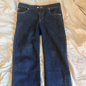 Mörkblå raka jeans - Snygga mörkblå jeans med klassisk femficksdesign och raka ben. Jeansen har kontrastsömmar och en enkel look som passar till det mesta. Tillverkade i jeansmaterial med en stilren finish. Det är midwiast men går att ha lowwaist